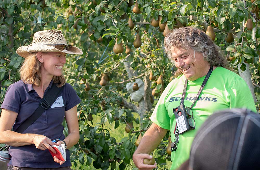 El productor Dain Craver y Tianna DuPont de la Universidad Estatal de Washington (WSU) ríen juntos durante uno de los días de campo de WSU dirigidos a productores más jóvenes en el huerto de KDS Orchards en Royal City, Washington. (TJ Mullinax/Good Fruit Grower)