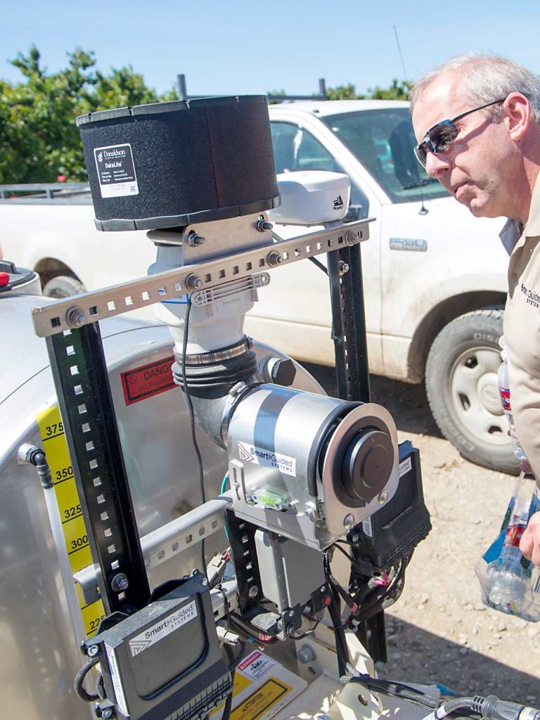 Steve Booher de Smart Guided Systems inspecciona el sensor LiDAR que guía la unidad de control de aspersión dirigida. (Ross Courtney/Good Fruit Grower)