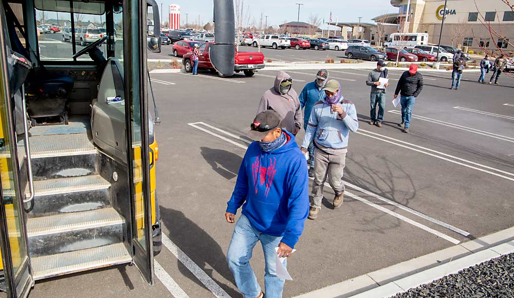 Papeles en mano, Jonathan González y sus compañeros H-2A de Washington Fruit and Produce Co. regresan a su autobús después de recibir la vacuna contra la COVID-19 de Johnson & Johnson en marzo en la Asociación de Salud de la cuenca de Columbia en Othello, Washington. (Ross Courtney/Good Fruit Grower)