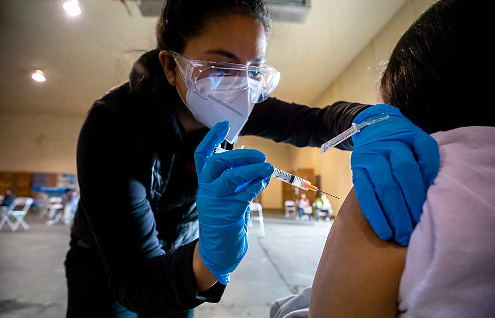 Guadalupe Zaragoza, enfermera de la Clínica de Trabajadores Agrícolas del Valle de Yakima, vacuna a Michelle Escobar contra la COVID-19 en una clínica para empleados a principios de abril en Hansen Fruit en Yakima, Washington. (TJ Mullinax/Good Fruit Grower)