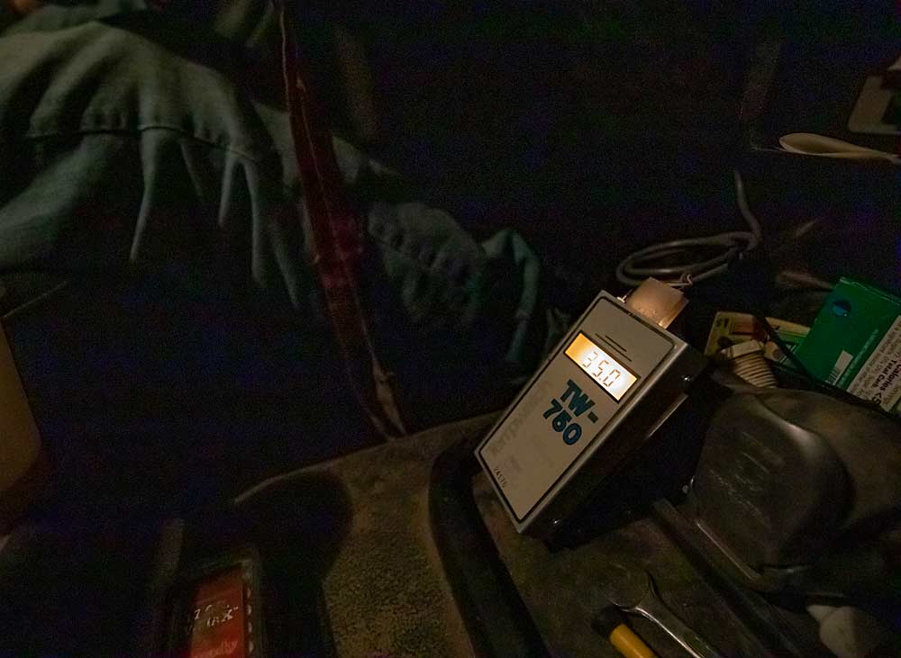 Durante sus fríos turnos de noche, Duim observa la lectura de este termómetro Tempwatch colocado en su camión. El termómetro está conectado a un sensor en la antena, que le permite a Duim evaluar las condiciones de inversión. En esta noche de abril, los puntos más altos del huerto alcanzaban los 35 grados Fahrenheit, mientras que los más bajos estaban a los 24 grados. "Puedo obtener una buena referencia de lo que hacen mis máquinas de viento", afirma. (TJ Mullinax/Good Fruit Grower)