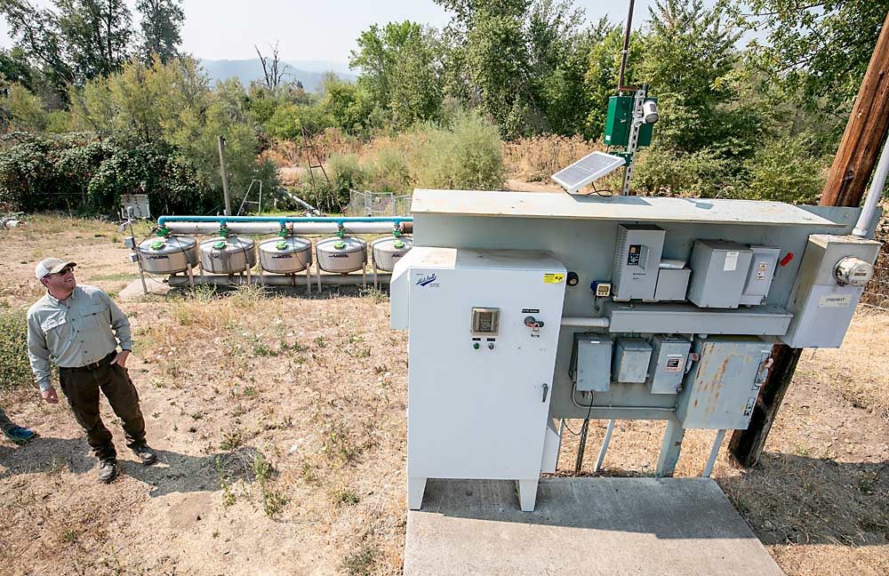 Josh Minchow, de Harry & David, explica cómo el equipo de bombas de los pozos con impulsadores de frecuencia variable y sistemas de automatización permitió a la empresa aprovechar al máximo el limitadísimo suministro de agua de Bear Creek, al fondo, en el 2022. (TJ Mullinax/Good Fruit Grower)