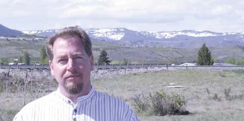 Jesse Lane stands on acreage planned by the Washington Growers League for a 126-bed project to help fill the housing needs of tree fruit seasonal workers. Stemilt Hill, near Wenatchee, Washington, is in the background.