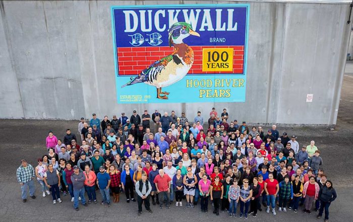 Duckwall Fruit current company staff stands outside their facility in Odell, Oregon, and a new mural celebrating the company’s 100 years of business in the Hood River Valley. (Courtesy Blaine Franger for Duckwall Fruit)