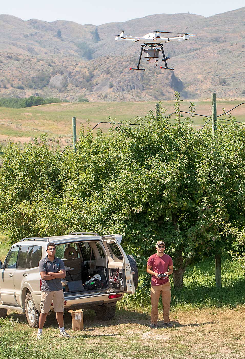Rodriguez, right, pilots a drone for a trial release while Moses-Howard looks on. Using drones allows the team to quickly move from orchard to orchard. (TJ Mullinax/Good Fruit Grower)