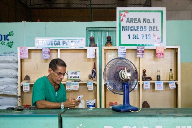 At a market in Havana, left, a vendor advertises his rice, sugar, beans, coffee and other staples as he checks his mobile phone. Notice the absence of Western branded goods. (O. Casey Corr/Good Fruit Grower)