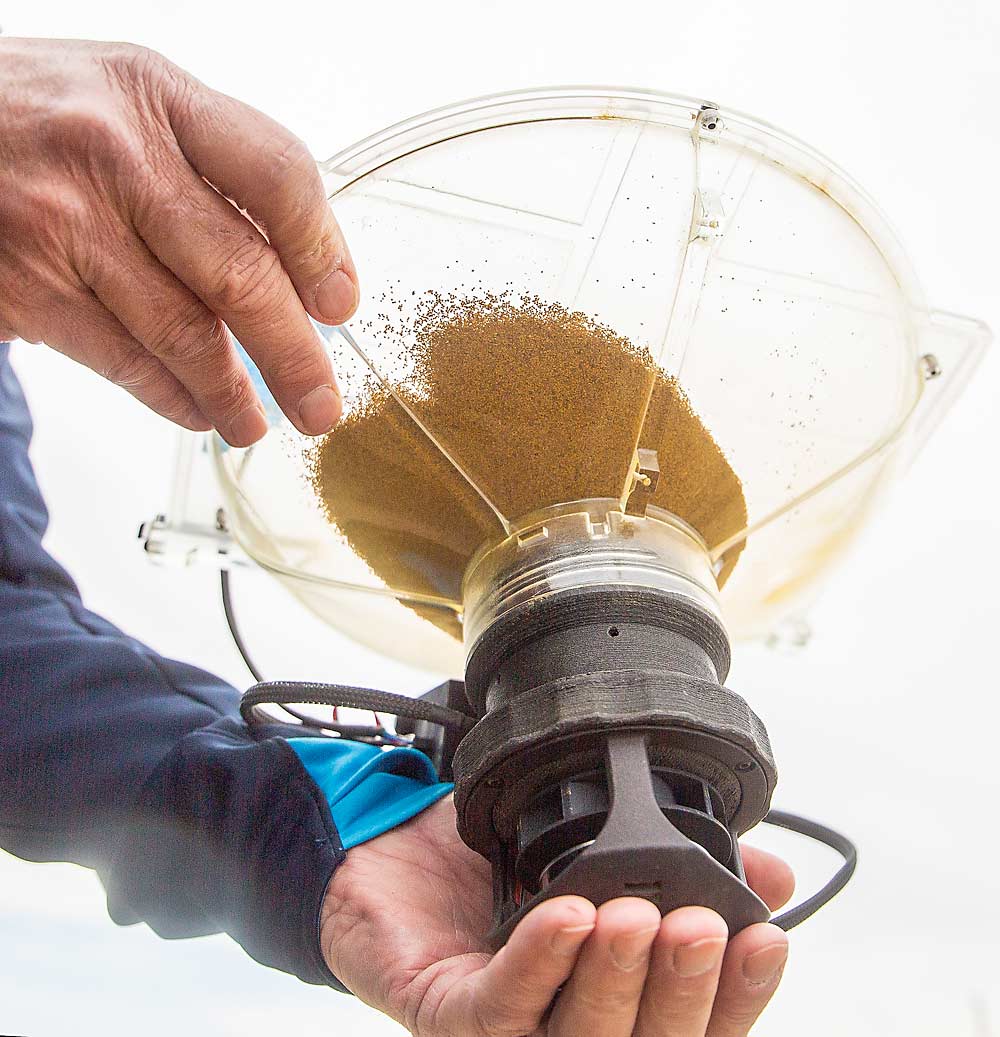 Tristen Svendsen, Dropcopter design engineer, loads pollen into a hopper for the drone to carry. (Ross Courtney/Good Fruit Grower)