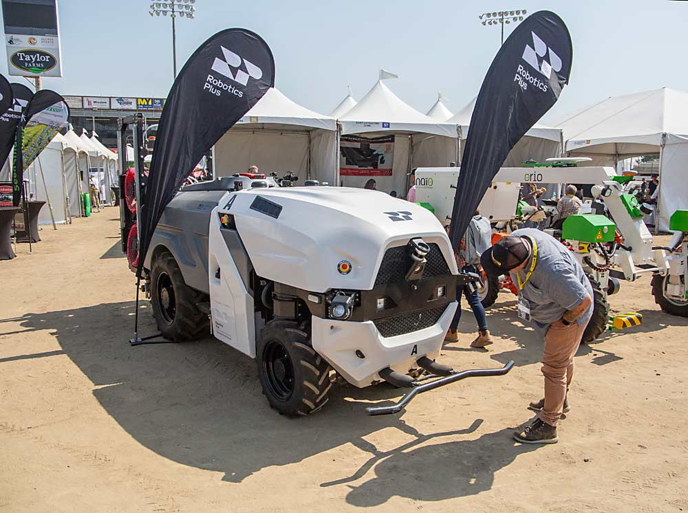 An attendee checks out the grill of a Robotics Plus self-driving, diesel/electric hybrid farm vehicle from New Zealand. (Ross Courtney/Good Fruit Grower)