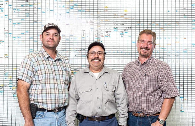 The management team of Lodi Farming, from left to right, Ray Avansino, Ezequiel Escamilla, and Jeff Colombini, stand in front of the hub of the company's operations'a white eraser board. The board, color coded by crop, lists upcoming farming tasks that need to be coordinated. TJ Mullinax/Good Fruit Grower