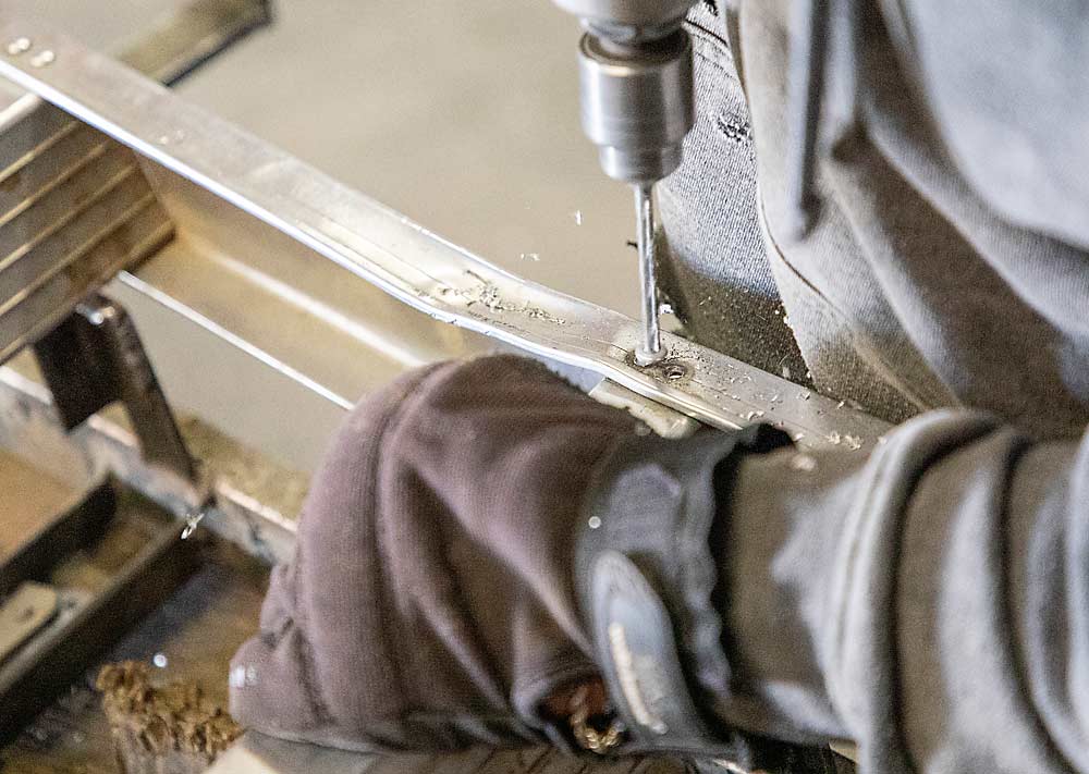 Elias Nuñez of Grandview Ladders drills out a rivet to replace a stretch of bent side rail. (Ross Courtney/Good Fruit Grower)