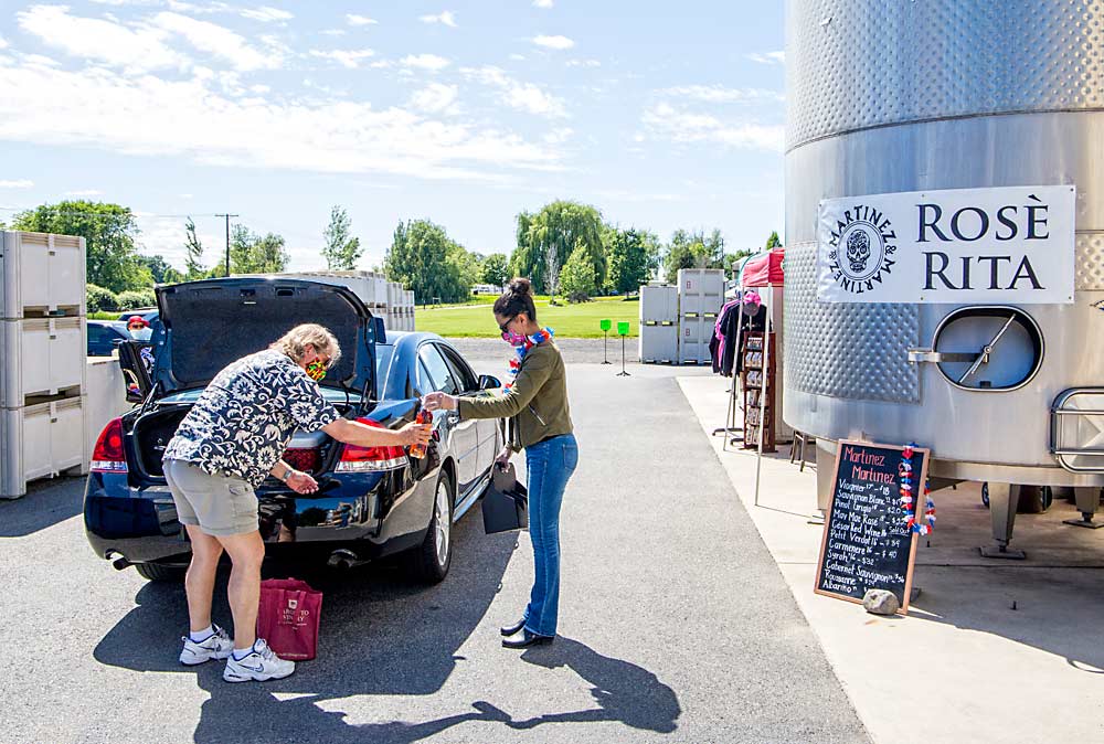 Karina Nyboer helps a customer load wine in the drive-through lane in May at Martinez and Martinez Winery in Prosser, Washington. This is one example of how wineries and vineyards are weathering the coronavirus pandemic. (Ross Courtney/Good Fruit Grower)