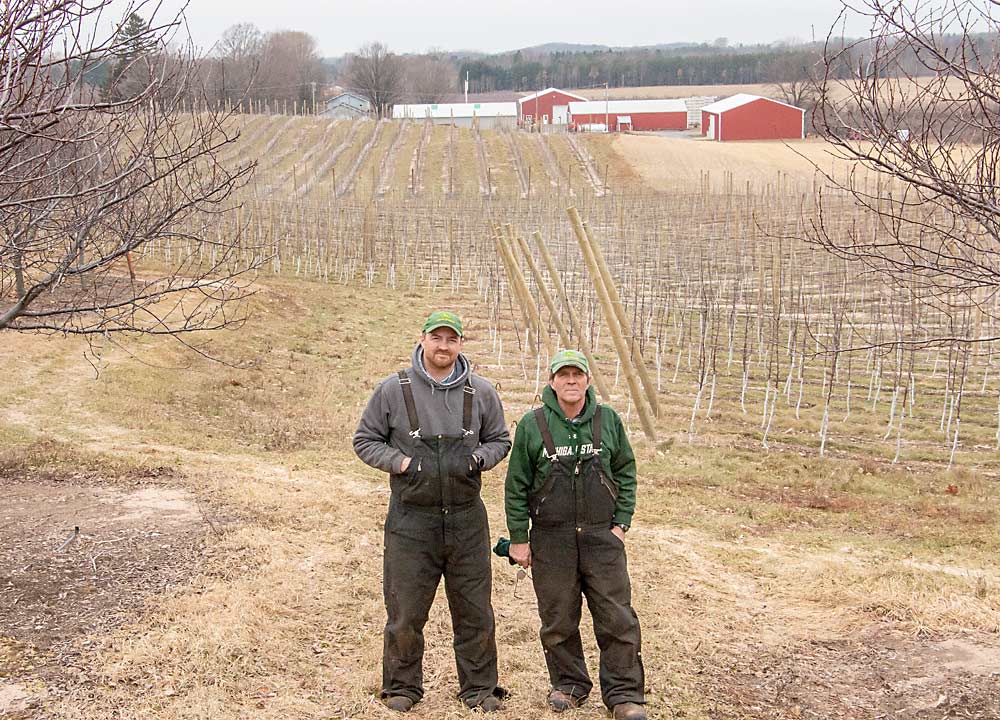 Andy Riley, left, and his father, Mark, stand in a row of tart cherry trees, overlooking blocks of modern, high-density apples. Fresh varieties such as Honeycrisp and Gala are taking over prime farmland once devoted to peaches and cherries in orchards throughout West-central Michigan. (Matt Milkovich/Good Fruit Grower)