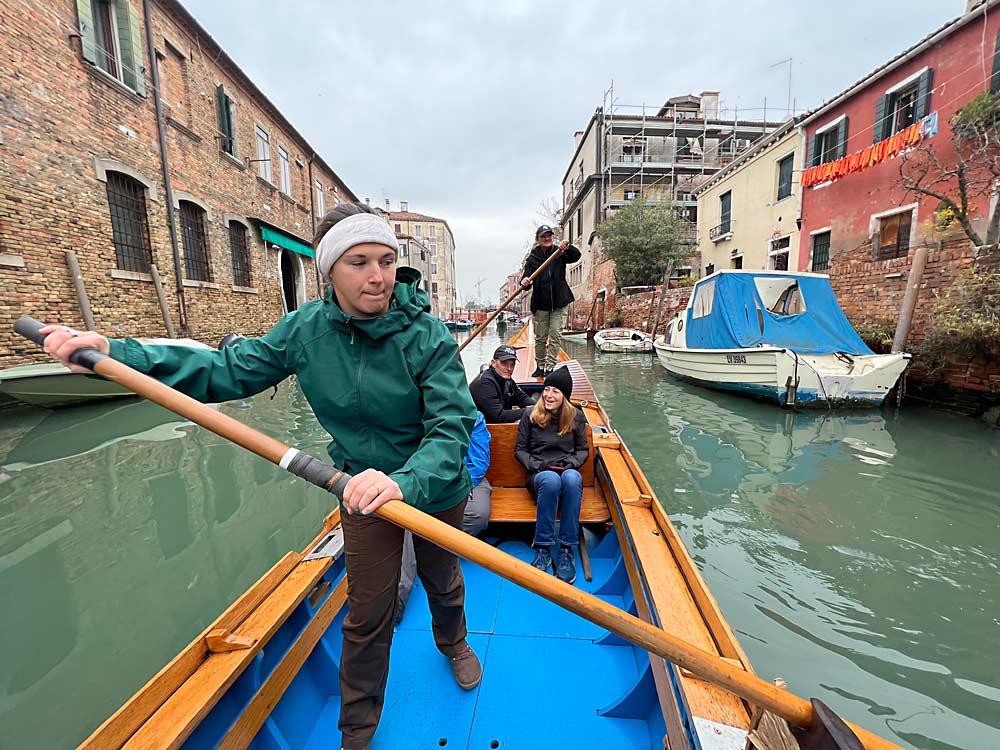 Suzanne Bishop of Allan Bros., a Yakima, Washington, fruit company, takes her turn propelling the batellina, a long, wooden boat similar to a gondola, in Venice. (Ross Courtney/Good Fruit Grower)