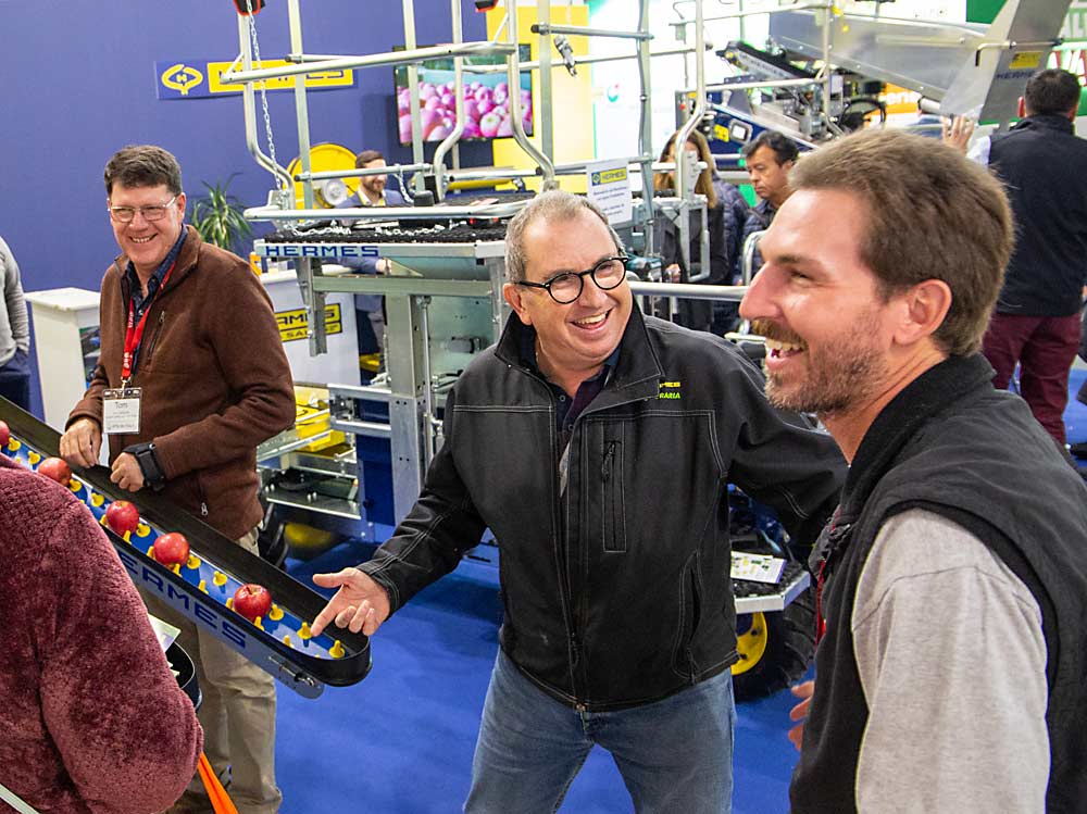 Stefano Veronese, second from right, of Italian farm equipment manufacturer Hermes laughs with Keim, right, and other International Fruit Tree Association visitors at the Interpoma trade show in Bolzano, South Tyrol, Italy. (Ross Courtney/Good Fruit Grower)