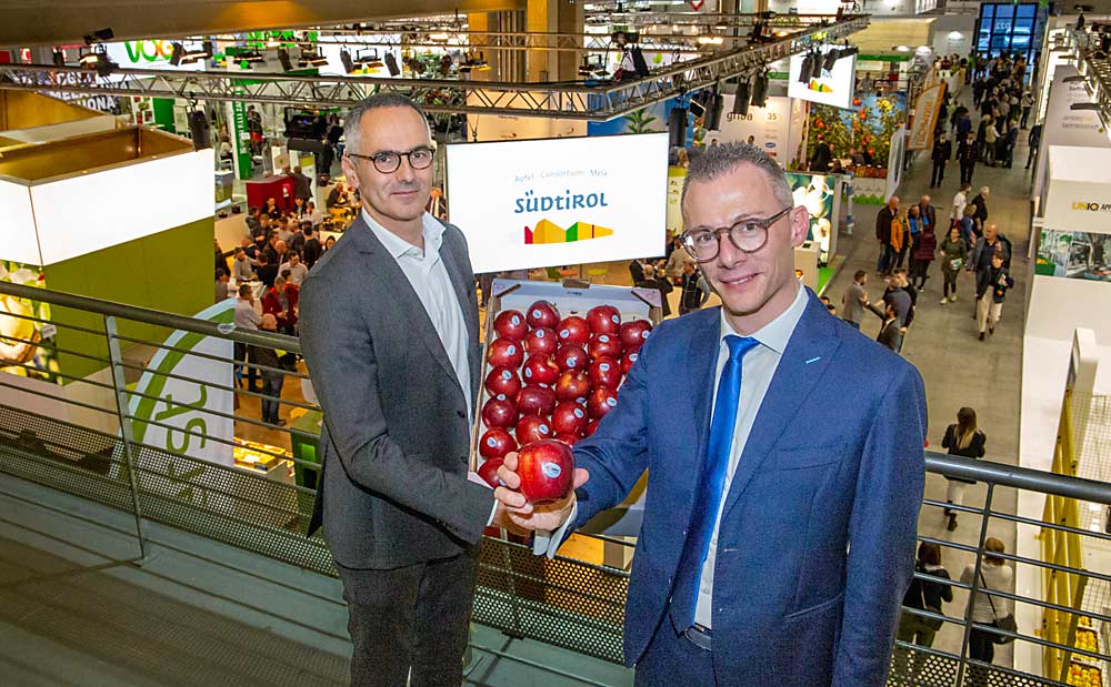 Walter Pardatscher of VOG, left, and Fabio Zanesco of VIP show off a box of Italian-grown Cosmic Crisps at the Interpoma trade show in November in the city of Bolzano, in South Tyrol, Italy, where producers have reached commercial production levels of Washington state’s signature apple. (Ross Courtney/Good Fruit Grower)