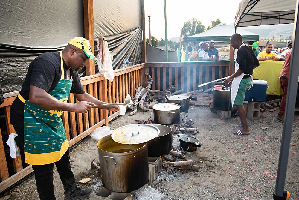 Leroy Harris, left, a 12-year Gebbers H-2A worker, ladles up some sauce for the chicken, pork and beef jerk. (Ross Courtney/Good Fruit Grower)