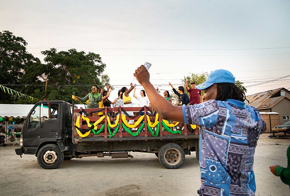 While his friends dance in the bed of a flatbed truck, Julian Bailey does his part on the ground. (Ross Courtney/Good Fruit Grower)