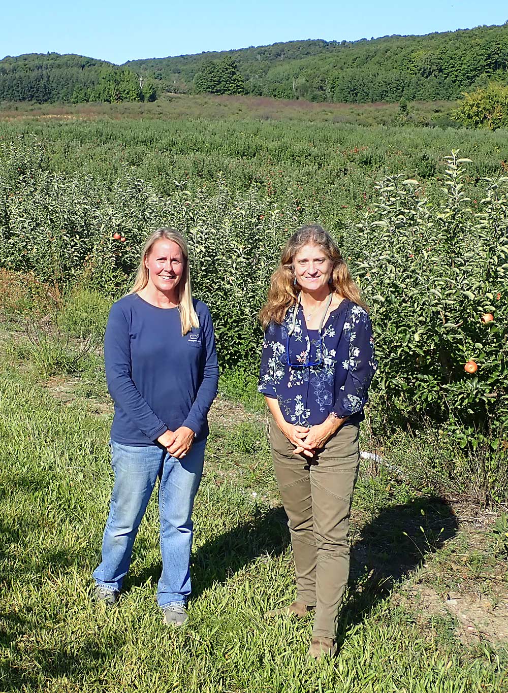 Kim Hayes, left, farmland and easement programs director for the Leelanau Conservancy, joins Michelle Kitts at the edge of the 217-acre Hohnke Farm in Cedar, Michigan, that Kitts and her husband, Greg, purchased last June. “From the hill, you can see the dunes, Manitou Island, Lake Michigan. It’s beautiful,” Michelle said. Land with views like that sells quickly and at a high price on the real estate market, but conservation easements such as the one on this farm typically moderate the price, which makes it more affordable for other farmers to purchase. Greg actually leased and farmed this land for a few years prior to purchasing it. (Leslie Mertz/for Good Fruit Grower)
