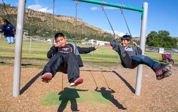 Third-graders Edgar Luna and Ricardo Mercado, whose parents work seasonally in nearby cherry orchards, swing at recess in June, during the Migrant Education Program at Chenowith Elementary School in The Dalles, Oregon. (Ross Courtney/Good Fruit Grower)