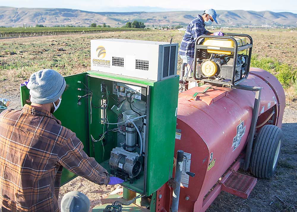 Schrader replaces fuses in the ozonation box while Rathnayake-Mudiyanselage troubleshoots the top-mounted generator during the trial. Coaxing the machinery into producing a consistent ozone concentration is part of the research, said Lav Khot, associate professor at WSU’s Center for Precision and Automated Agricultural Systems, and principal investigator of the ozone project. (Ross Courtney/Good Fruit Grower)