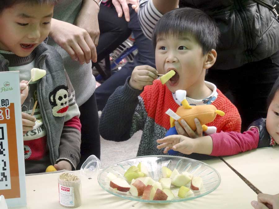 Photos courtesy of Pear Bureau Northwest A boy chomps into a pear slice at a stop in China along the USA Pear Road Show, a promotion of Pear Bureau Northwest. In a routine vote, growers in Washington and Oregon are being asked to approve continuing the marketing order that allows such generic promotions. (Courtesy Pear Bureau Northwest)