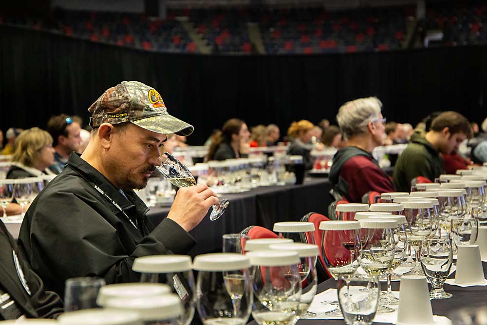 Gerardo Cambron, cellar lead for Col Solare winery, sniffs a glass of sparkling Grosgrain Vineyards 2022 Lemberger Blanc de Noir on Feb. 7 during the Grand Tasting at WineVit, the annual convention of wine grape growers, at the Toyota Center in Kennewick, Washington. (Ross Courtney/Good Fruit Grower)