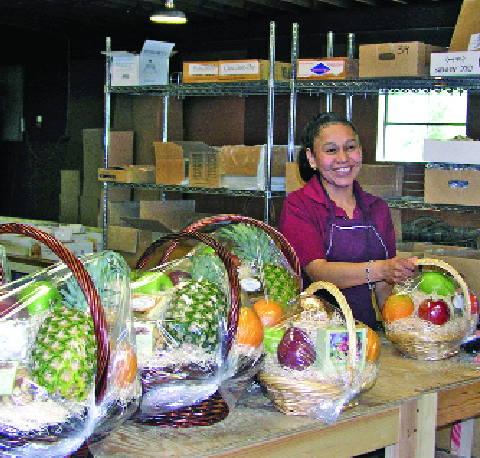 Concepcion Morales and Maria Vega (right) add finishing touches  to gift baskets, which are offered in a wide range of sizes.  Photo by Geraldine Warner