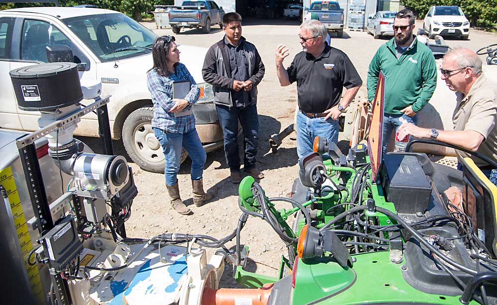In the center, Gregg Marrs, owner of Blueline Manufacturing, describes the workings of the Smart Guided spray control on his company’s Accutech sprayer at Bosma Orchards. Listening are, from left, Julie Bosma, Angel Aguilar, Dustin Heyen and Steve Booher. The farm already owns a spray control unit but is interested in purchasing more, so Bosma organized the May demo to test it on an upgraded sprayer. (Ross Courtney/Good Fruit Grower)