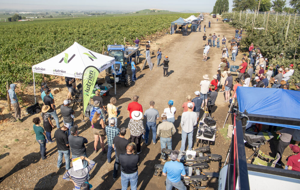 A crowd of well over 100 people circle around Washington State University’s Bernardita Sallato discussing nutrient optimization during a field day on Aug. 2, at the Smart Orchard near Grandview, Washington. (Ross Courtney/Good Fruit Grower)