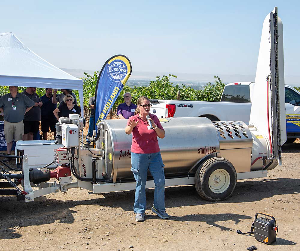At a field day, Washington State University researcher Gwen Hoheisel explains the research project in front of the Turbo-Mist sprayer and the Smart Apply kit attached to the front. (Ross Courtney/Good Fruit Grower)