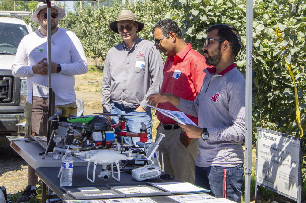 From left to right, Nathan Santo Domingo, Sean Hill, Lav Khot and Gajanan Kotha-wade, all with Washington State University, share information about AgWeatherNet and drone imaging technology at the Smart Orchard field day on July 26 in Grandview, Washington. (Jonelle Mejica/Good Fruit Grower)