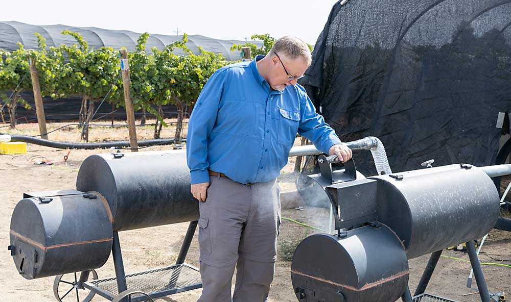 Tom Collins, an assistant professor of wine science at WSU, checks to make sure the fuel level — in this case commercial smoker pellets — is sufficient in the midst of a 36-hour smoke treatment just before harvest of Cabernet Sauvignon in late September at WSU’s research vineyard in Prosser. (Kate Prengaman/Good Fruit Grower)
