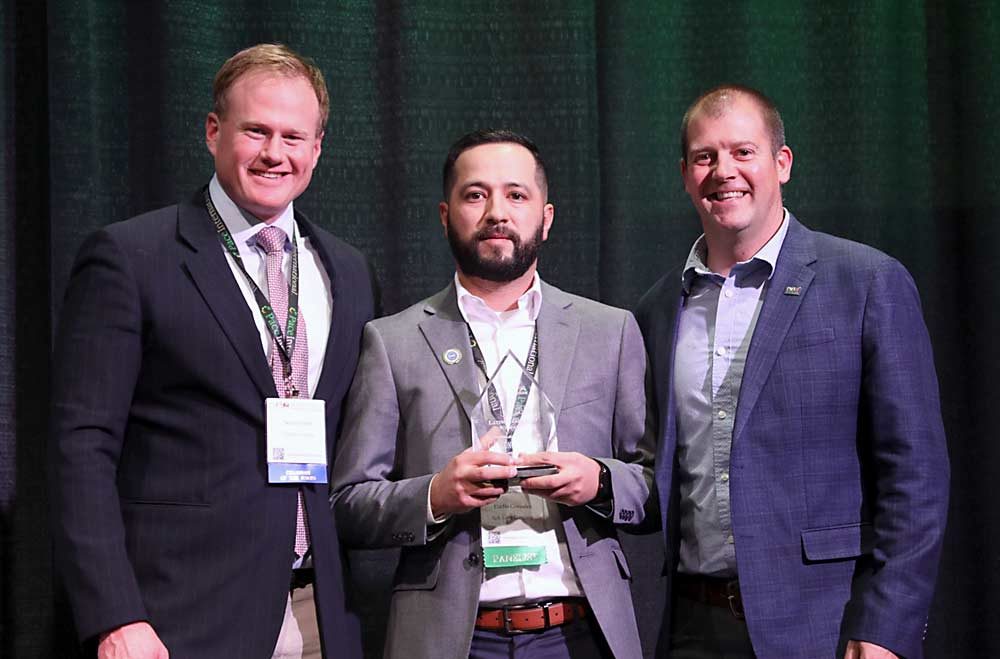 G.S. Long Company, represented by Eladio Gonzales, center, is presented the Latino Leadership award on Dec. 10, 2019, by Sean Gilbert, left, and Mark Hambelton, right, during the 115th Washington State Tree Fruit Association Annual Meeting banquet. (TJ Mullinax/Good Fruit Grower)