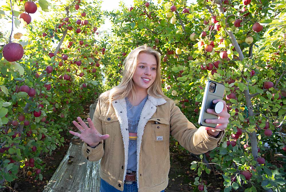 Farmfluencer Kaitlyn Thornton, known in the fruit industry and beyond for her freehand, selfie videos, makes one about her video-production process — sharing tips for less social media-savvy growers — in October in a Fuji block near Wenatchee, Washington. (Ross Courtney/Good Fruit Grower)