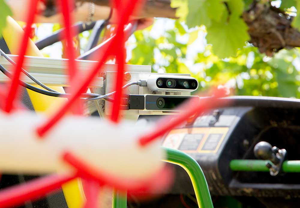 The hurdle in automating shoot thinning is getting the camera, seen here at center, to continuously track the trajectory of the cordon and move the thinning whips up, down, in and out, accordingly, in real time. (Ross Courtney/Good Fruit Grower)