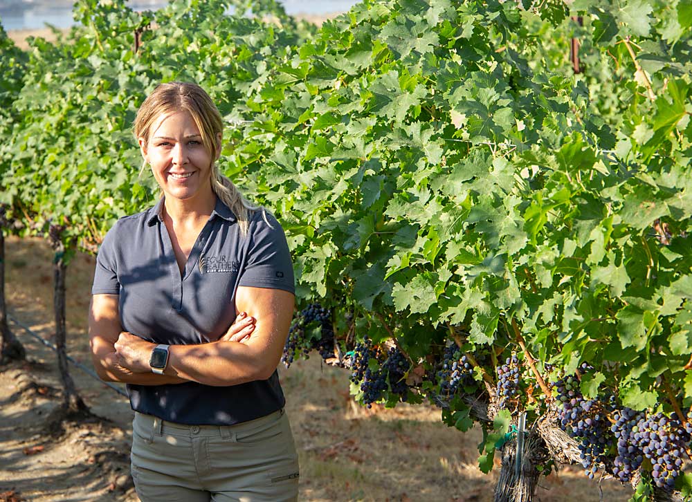 Carly Faulk of Four Feathers Wine Services poses in August near Cabernet Sauvignon grapes near McNary, Washington, that are part of the company’s Grape Marketplace. Instead of only managing vast tonnage for one or two clients, grape growers are diversifying to meet the needs of many boutique wineries. (Ross Courtney/Good Fruit Grower)