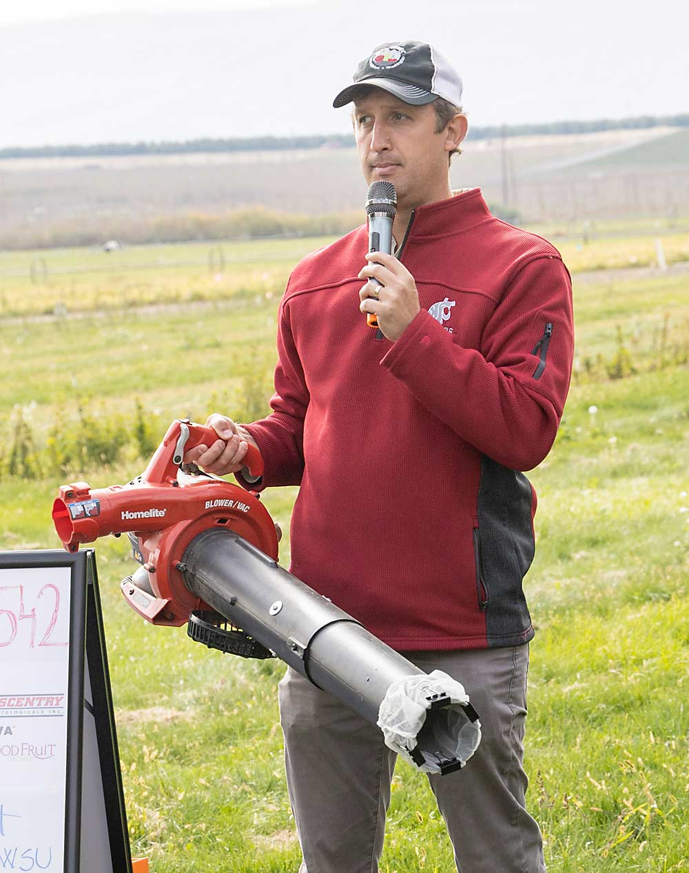 Washington State University entomologist Tobin Northfield shows how he uses a leaf blower, running backward and outfitted with a paint bag, to suction up leafhoppers from perennial weeds on the orchard floor during a field day WSU organized at the Roza research farm on Oct. 9 to share the latest findings on management of the leafhoppers that are vectors for X disease. (Kate Prengaman/Good Fruit Grower)