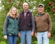 Three generations of Wittenbachs — Elizabeth, her father, Mike, and her grandfather, Ed — pause in the test plot, which includes seven new varieties from Washington. Elizabeth is particularly intrigued by newly released cultivars and looks forward to seeing how well the options fare in the orchard. (By Leslie Mertz)