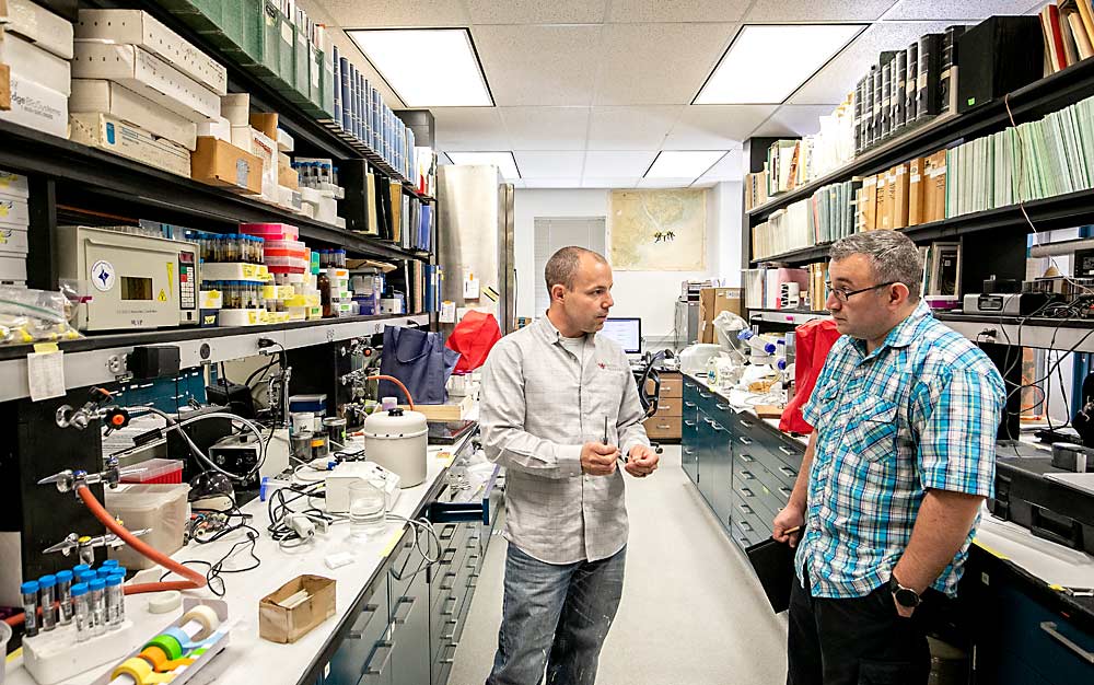 Brandon Hopkins explains to Jason Bragg of the West Virginia Queen Producers Cooperative how the lab makes its own glass vials by heating, stretching, breaking and fire polishing long glass capillary tubes. As far as Hopkins knows, nobody produces such vials commercially, so he and his team make their own. (TJ Mullinax/Good Fruit Grower)