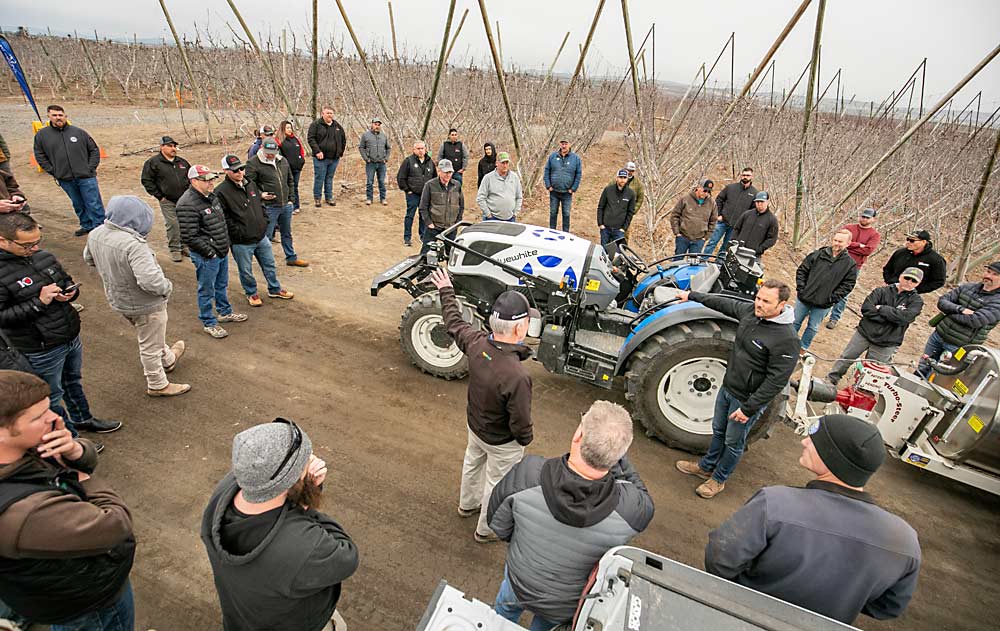 Grower Bruce Allen, center, addresses a question to Bluewhite director of partnerships Luke Hemphill, next to tractor, during an autonomous tractor demonstration for tree fruit growers near Granger, Washington, in March. Pacific Northwest growers are starting to buy the Pathfinder technology from robotics company Bluewhite. (TJ Mullinax/Good Fruit Grower)