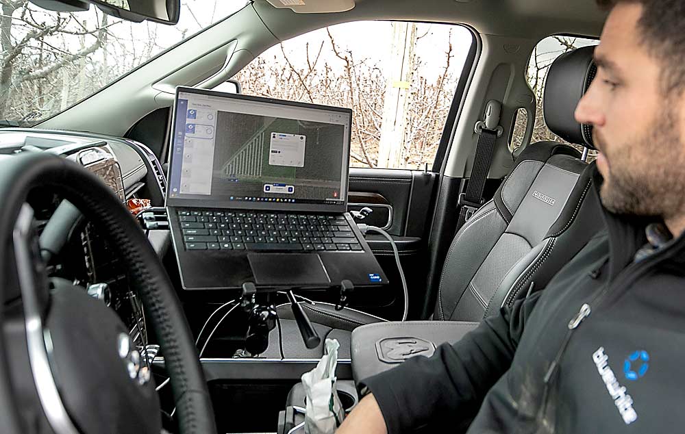 Bluewhite’s Yanir Ariav operates the Pathfinder-equipped tractor via laptop. When running multiple tractors, only two workers are needed: the operator and someone to refuel the tractors and refill sprayers. (TJ Mullinax/Good Fruit Grower)