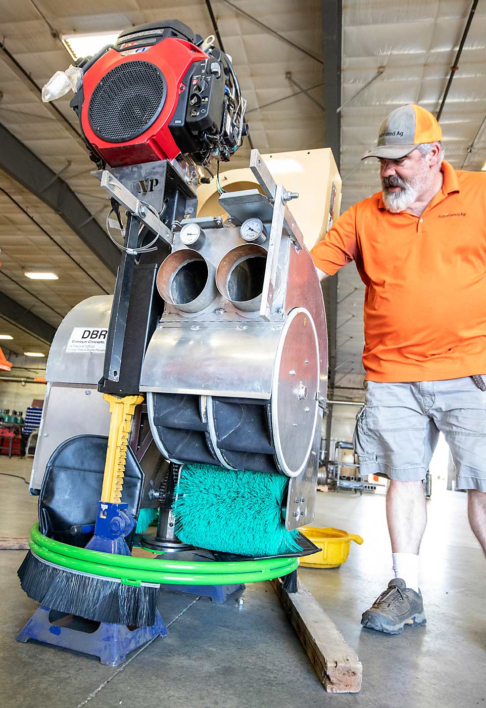 JJ Dagorret shows several of the changes he made to the prototype vacuum harvest machine at Automated Ag Systems in June. The only thing remaining from the original bolt-on version is the decelerator in the center of the machine built by DBR Conveyor Concepts. From top: The original high-RPM engine was replaced with a quieter engine, the vacuum fan blade and housing was redesigned to create more suction, and the optical bin delivery system was replaced with a pre-existing mechanical delivery system developed by MAF Industries. Dagorret says this new version was redesigned based on grower feedback. (TJ Mullinax/Good Fruit Grower)