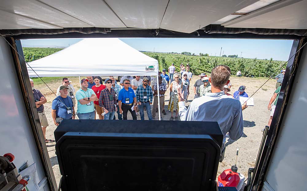 IFTA 2022 Summer Tour attendees listen to technology updates from Smart Orchard project coordinator, and founder of innov8.ag, Steve Mantle, seen from inside his mobile ag data center that he brings to remote farms to process the video data collected by the Green Atlas Cartographer and other data-heavy sensors. (TJ Mullinax/Good Fruit Grower)