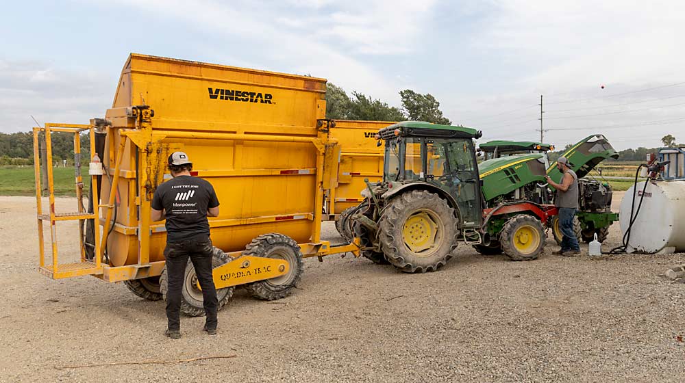 Jack Walker, left, and Eric Marsh prepare a gondola and tractor before harvest at Arrowhead Vineyards in Southwest Michigan in October 2023. The gondola paces the grape harvester, which fills it with grapes that are then dumped into semi-trailers. Arrowhead owner Dan Nitz machine harvests most of his wine grapes. (Matt Milkovich/Good Fruit Grower)