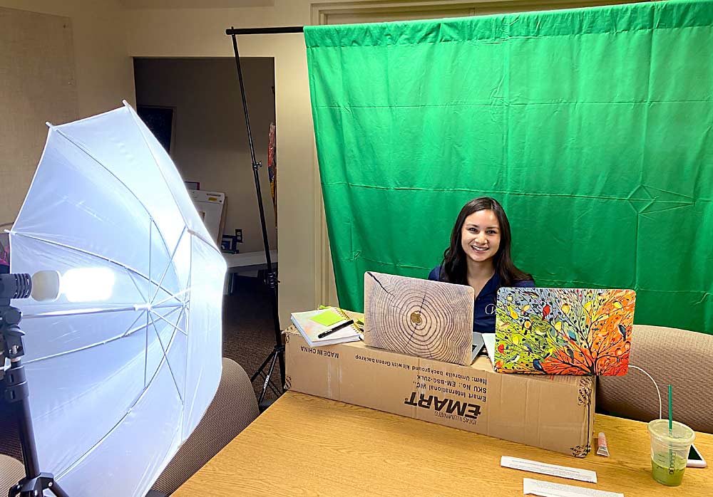 Erika Betancourt, the scholarship specialist for the Washington Apple Education Foundation, sets up the Wenatchee office as a makeshift studio to film educational clips about how to search for and fill out scholarship applications, training that the organization would normally do in person at high schools throughout the state’s growing region. The foundation and fruit industry groups throughout the world are pivoting, rescheduling and rethinking their outreach events under the restrictions of the coronavirus pandemic. (Courtesy Jennifer Witherbee/Washington Apple Education Foundation)