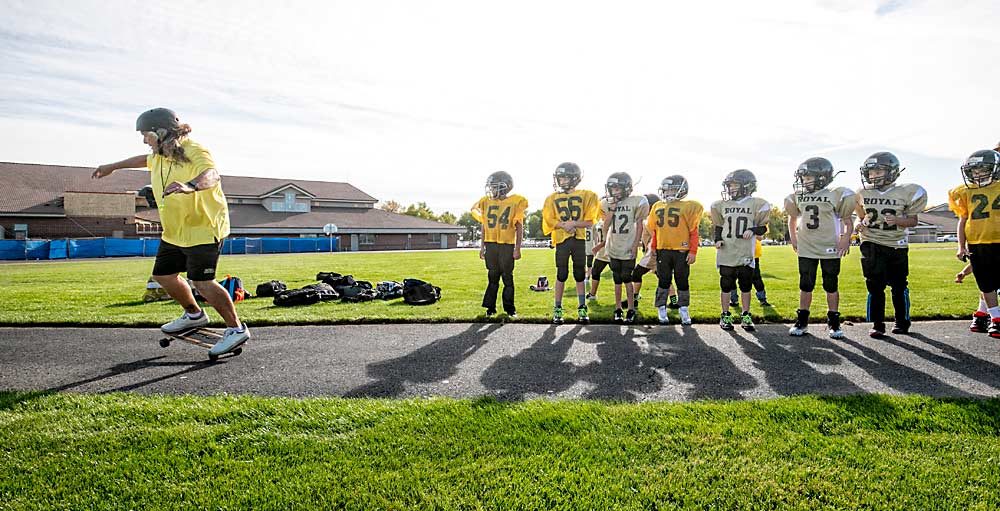 Craver demonstrates a few skateboarding skills to his third-grade football players. Big hair and skateboarding aside, Craver is known throughout the tree fruit industry for his personality as well as his skills as an organic grower. (TJ Mullinax/Good Fruit Grower)