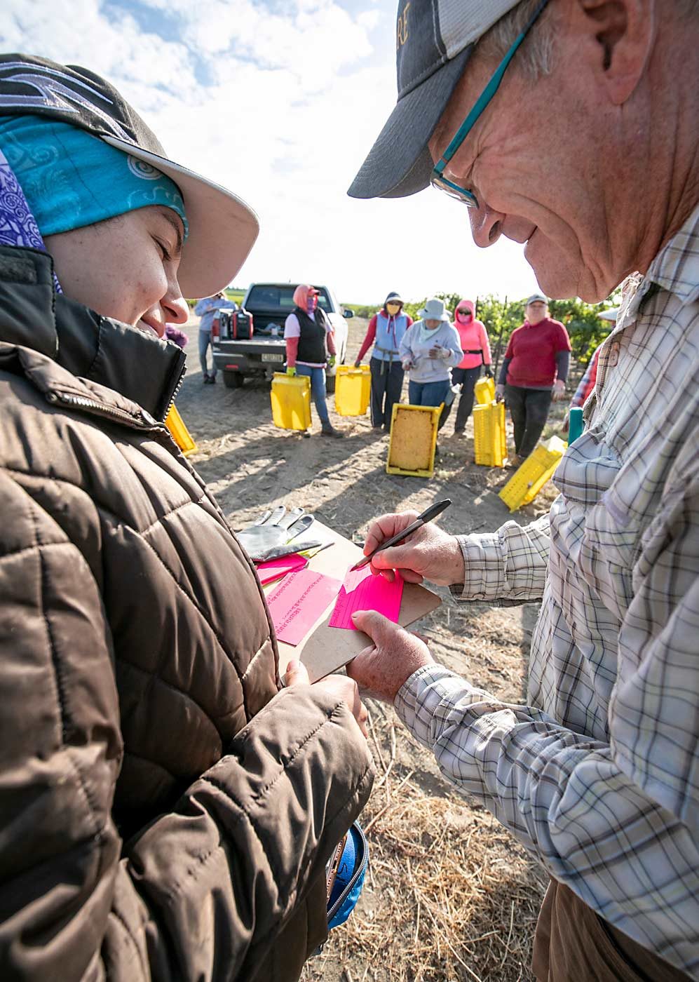 Boushey, right, fills out grape harvest cards with Elia Medina before his crew begins harvesting at Grand Ciel Vineyard. (TJ Mullinax/Good Fruit Grower)