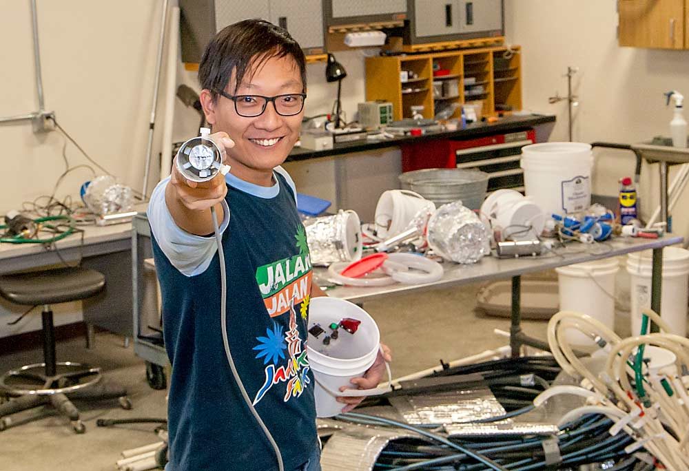 Ben-Min Chang, a Washington State University researcher, aims his self-built infrared radiometer at the camera. It connects to a mist cooling system for wine grapes that he’s developing at WSU’s Irrigated Agriculture Research and Extension Center in Prosser. (Ross Courtney/Good Fruit Grower)