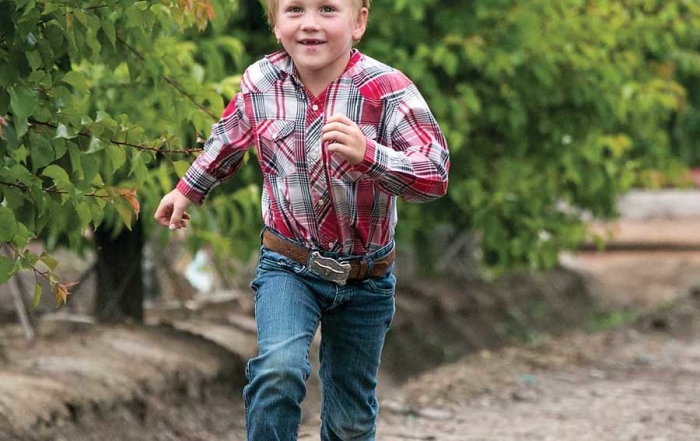 David Muxlow, part of a future generation of Family Tree Farms growers, runs to his father, Andy, in Reedley, California on April 9, 2015. (TJ Mullinax/Good Fruit Grower)
