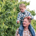 Jonathan Muxlow sits on his father, Andy Muxlow's shoulders, as they look at cherries and nectarines at the Family Tree Farms test orchard in Reedley, California on April 9, 2015. (TJ Mullinax/Good Fruit Grower)